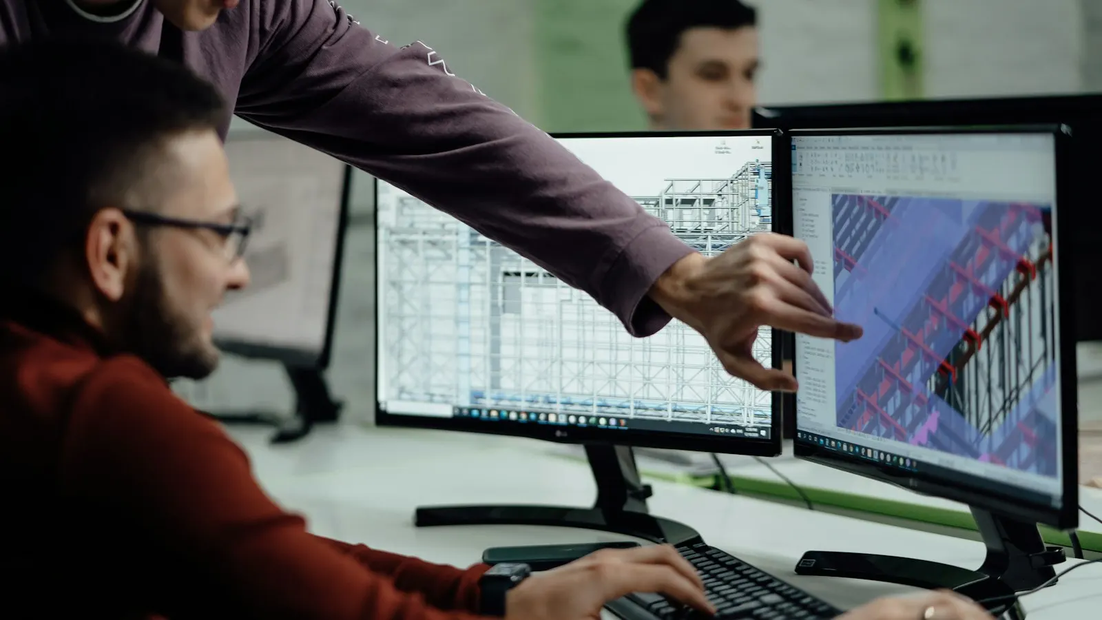 Two technicians review a BIM model of a building on two monitors